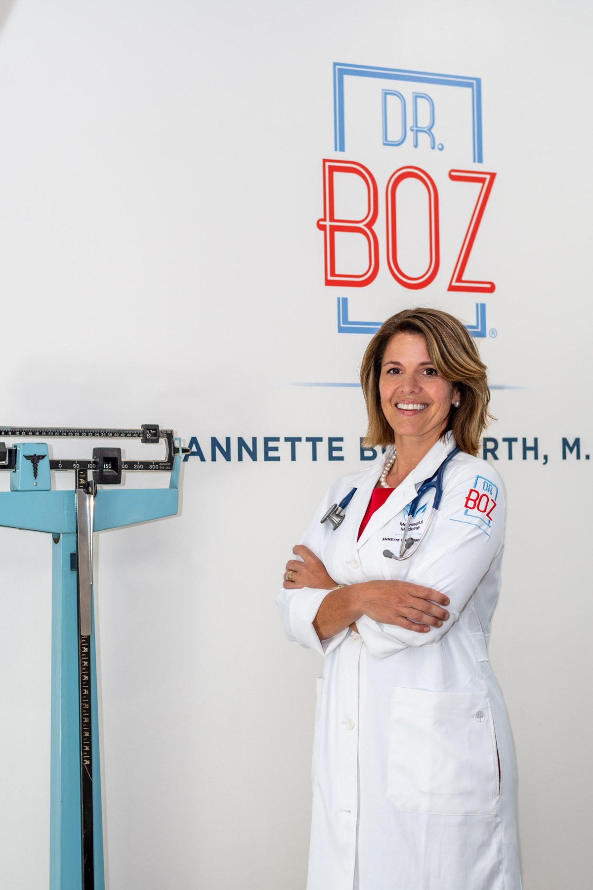 Dr. Annette Bosworth in her white coat, arms crossed, in front of the Dr. Boz logo.